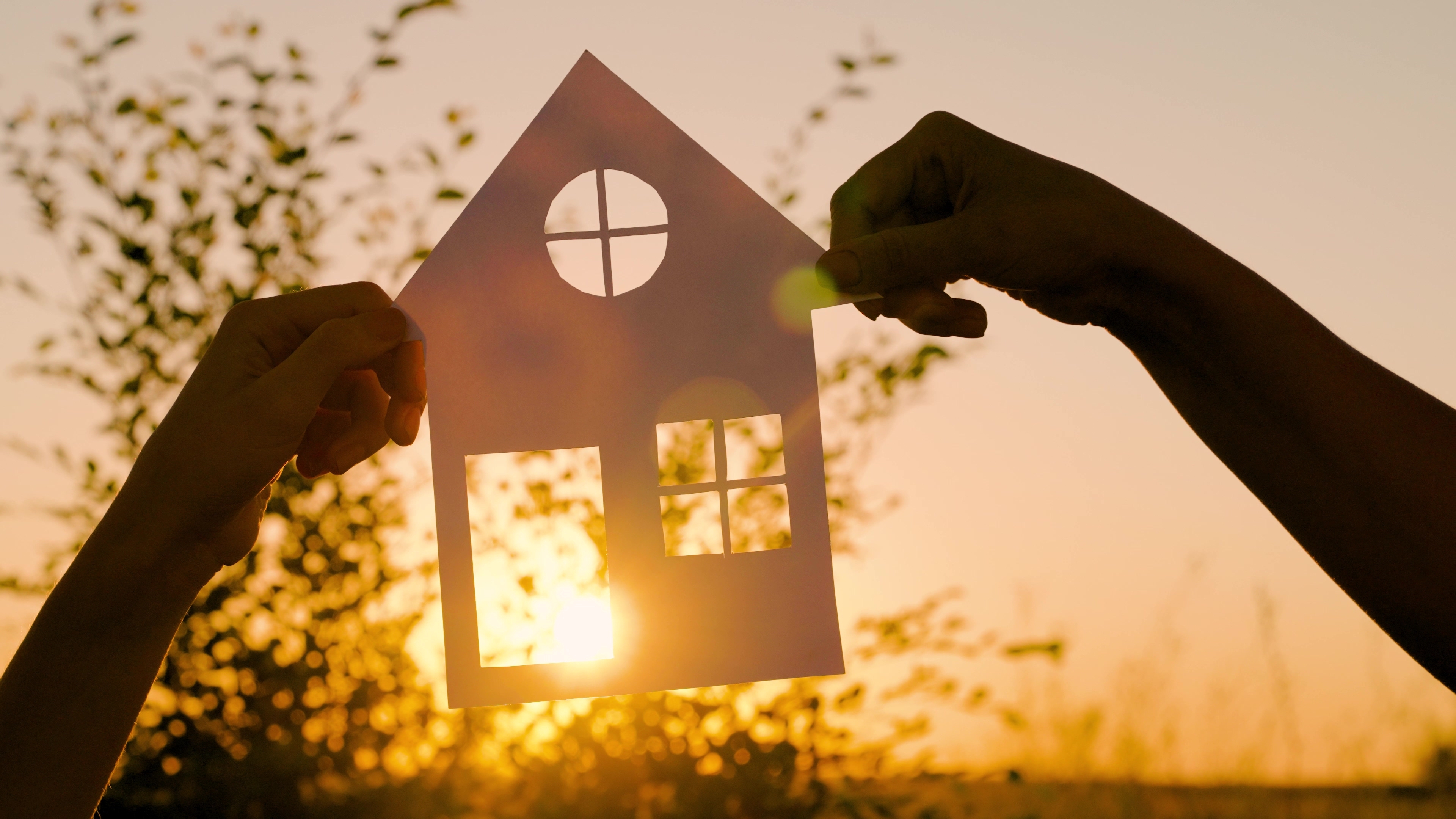 An image of a paper house held up to the sun representing a dream house